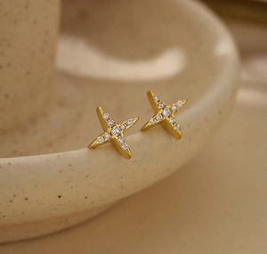 Macro shot of gold star earrings with pavé zircon details resting on ceramic