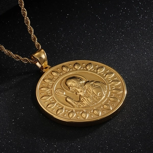Close-up of golden Saint Benedict round pendant with rope chain on dark background