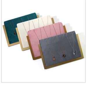 Detailed view of velvet necklace display stands in green, beige, pink, and grey with gold trim