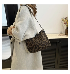 Close-up of leopard print shoulder bag with wide strap on model in beige coat