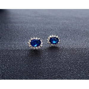 Macro shot of halo design earrings featuring oval blue gemstones and crystal borders