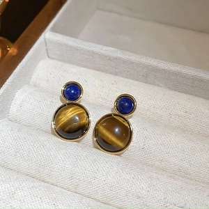 Detailed close-up of tiger eye and lapis blue stones set in gold earrings on a jewelry box