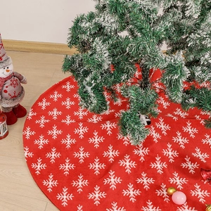 Red Christmas tree skirt with white snowflake jacquard patterns on wooden floor