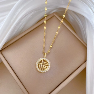 Macro detail of a gold titanium necklace with Fu character pendant and pavé zircons