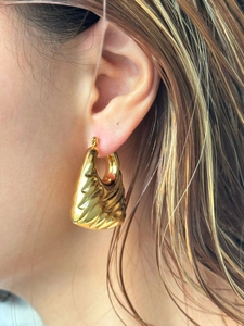 Macro side view of large hollow 18k gold plated hoop earrings with ribbed pleated texture