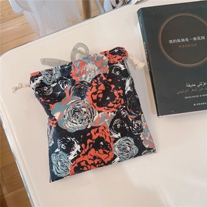 Detail of floral drawstring pouch with orange roses and a grey hair claw clip