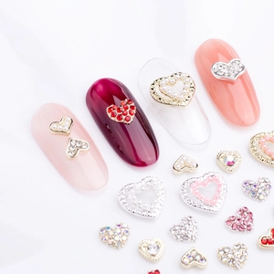 Detail of 3D alloy heart nail charms with rhinestones and pearls on various nails