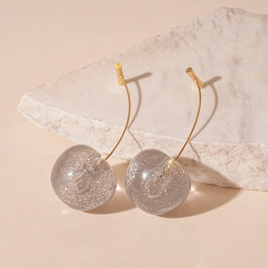 Detail of sweet cherry-shaped resin earrings with grey glitter and gold hooks