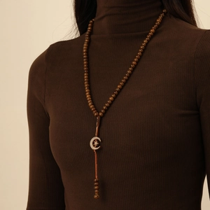 Detail of dark brown wooden prayer beads with star and crescent pendant on a knit sweater