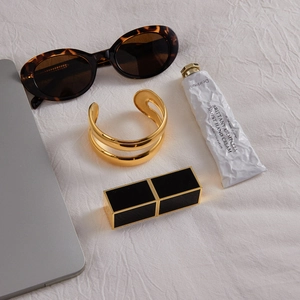 Top view of a gold double-layer open bangle with resin detail on a soft fabric background