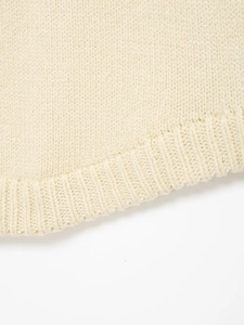 Detailed macro view of beige knit vest featuring wide ribbed hem and premium texture