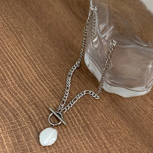 Détail du pendentif en perle baroque et du fermoir à bascule argenté sur collier