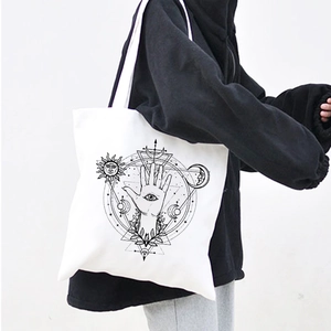 Close-up of Harajuku style canvas tote bag with Egyptian eye and moon pattern
