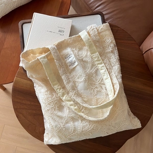 Detail of floral lace embroidery tote bag on wooden table with warm lifestyle ambiance