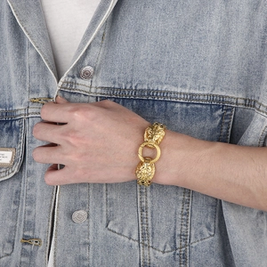 Detailed close-up of golden lion head clasp on a heavy stainless steel chain bracelet