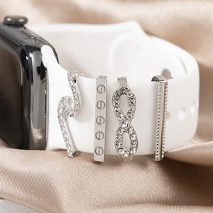 Macro detail of four silver decorative charms with rhinestones on champagne silk fabric
