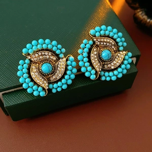 Close-up of vintage gold earrings with turquoise beads and rhinestones in jewelry box