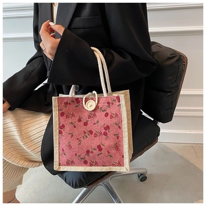 Detailed view of floral pattern handbag with hemp rope handles and wooden button accent