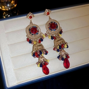 Detailed close-up of golden Jhumka earrings with colorful beads and red water drop pendants