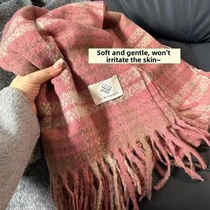 Detail of pink and brown plaid knitted scarf with long fringe and brand label