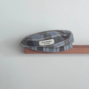 Detail view of children's plaid beret with woven wool texture and embroidered patch