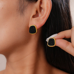 Detailed close-up of retro flocking geometric gold earrings with black matte inlay