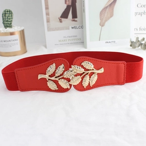Elastic red dress belt featuring a decorative golden leaf buckle on a white background