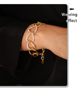 Detail of chunky gold and silver chain bracelet with rhinestones worn on a model