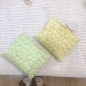 Macro detail of soft quilted flower texture on light green and yellow padded cosmetic bags