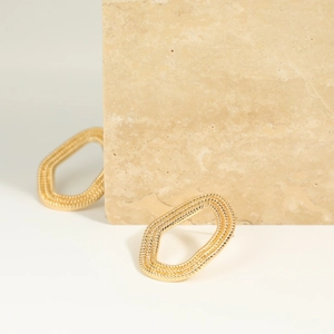 Gouden ovale gedraaide creolen in touwstijl op een minimalistisch stenen display