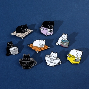 Close-up of eight black and white cat enamel pins featuring pet friendly text and cute designs