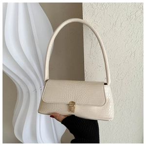 Detail of beige faux crocodile leather handbag with elegant gold twist lock and handle