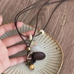 Détail d'un collier bohème avec pendentif en bois et breloque étoile de style vintage