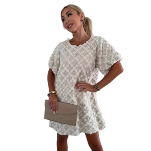 Gros plan sur une robe blanche à texture florale 3D, manches bouffantes et pochette chic