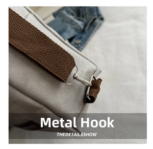Detail of durable metal hook and woven shoulder strap on a grey multi-purpose tote bag