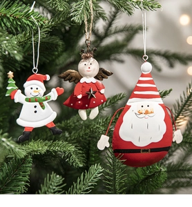 Macro detail of painted metal snowman and angel ornaments on a glowing Christmas tree
