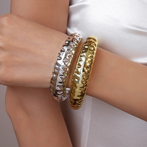 Detailed view of chunky irregular hammered texture metal cuffs in gold and silver finish