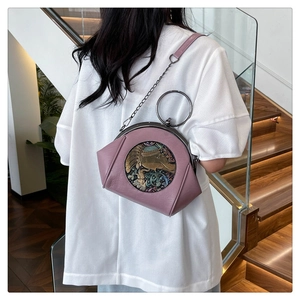Detail showing purple leather bag with metal elephant relief and chain strap on model
