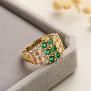 Detail of gold geometric wide ring with micro-paved green and white zircon in jewelry box