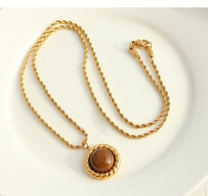 Close-up of a vintage golden twist chain necklace with round brown tiger eye pendant