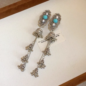 Close-up of ethnic silver tassel earrings with turquoise, pearls, and mini bells