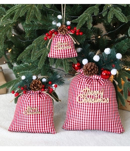Close-up of red and white plaid Christmas gift bag with pine cones and wood tag