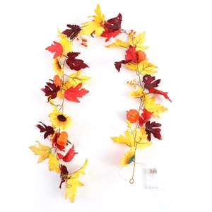 Close-up of autumn garland with maple leaves, pumpkins, sunflowers and battery pack