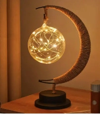 Close-up of decorative moon-shaped lamp with twine wrapped frame and glowing LED glass sphere