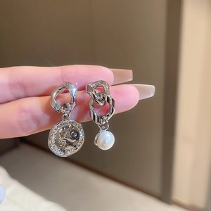 Detail of asymmetric silver chain earrings with portrait coin and faux pearl drop