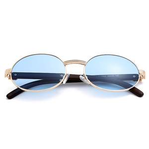 Detalle de gafas de sol ovales con lentes azul claro y patillas con textura de madera
