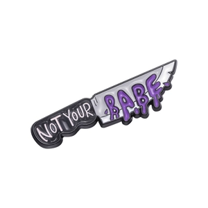 Detail of purple dagger enamel pin featuring handwritten Not Your Babe text on metal