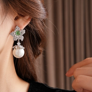 Gros plan d'une boucle d'oreille fleur vintage avec gemme verte et grande perle
