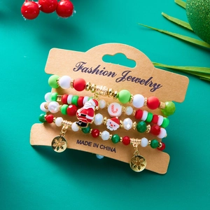 Set of four Christmas beaded bracelets with Santa Claus and snowflake charms on green background