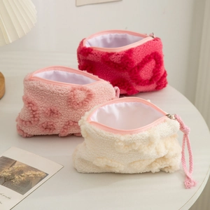 Detail of plush cosmetic bags with heart patterns, zippers and pink cord pullers